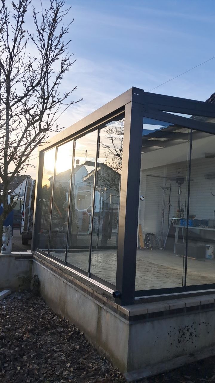 Geschlossene Glasschiebewand einer Alu-Terrassenüberdachung in der Abendsonne