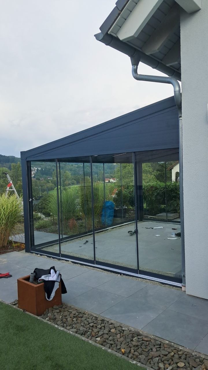 Freistehende Alu-Terrassenüberdachung mit Glasschiebewand in Hanglage